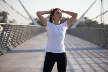 Sports woman in a white T-shirt while training on the bridge. Mock-up.