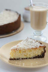 slice of a cheesecake with a cup of coffee on a white background