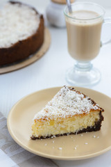 slice of a cheesecake with a cup of coffee on a white background