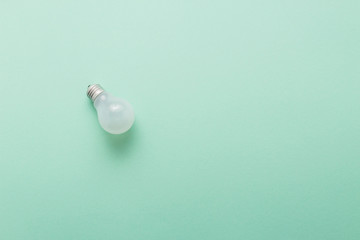 Light bulb on pastel green background top view, flat lay with copy space