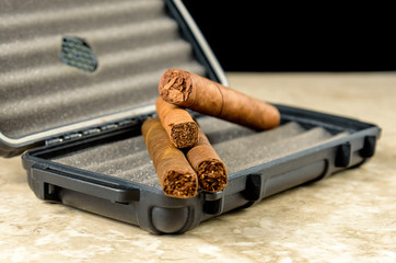 Cigars on top of a black travel humidor. Rich smelling and textures of tobacco leaves