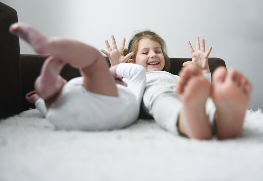 Little girl is smiling laying with her baby brother. Photo with soft focus on a girl.