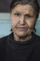 Portrait of an elderly woman. A thoughtful grandmother sits in a room.