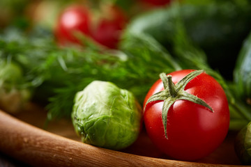 Vegetarian still life of fresh vegetables on wooden plate over rustic background, close-up, flat lay.
