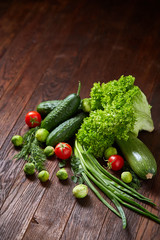 Vegetarian still life of fresh vegetables on wooden plate over rustic background, close-up, flat lay.