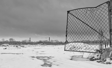 Broken open metal gate leading to the industrial zone outside of the city