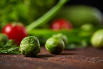 Vegetarian still life of fresh vegetables on wooden plate over rustic background, close-up, flat lay.