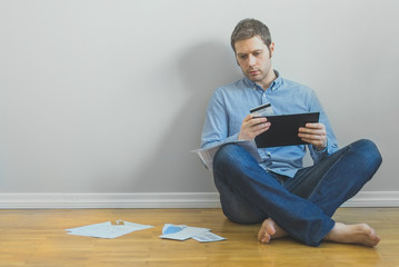 Handsome man using tablet pc and credit card to pay bills.