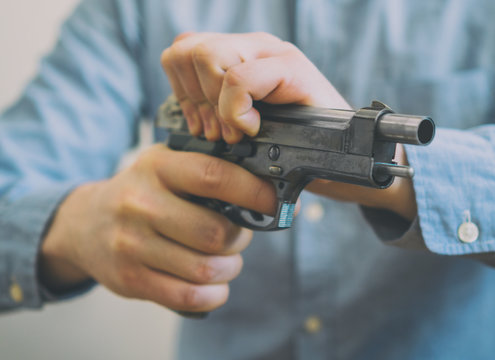 Male hands reloading gun. Close-up view.
