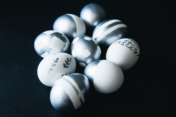 Group of diverse silver Easter eggs on black background, original stylish idea, selective focus