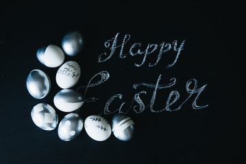 Group of diverse silver Easter eggs with Happy Easter inscription on black background, original stylish idea, selective focus