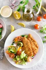 Salad from tomato, zucchini, radish, greens and schnitzel