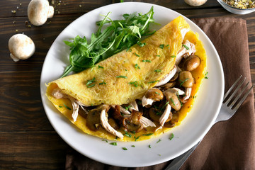 Omelet stuffed with mushrooms, pieces of chicken meat, greens