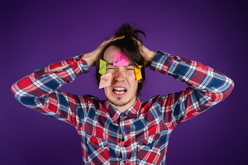 Man grabs his head, cries with his eyes closed and his mouth open, stickers on his face. A man is...