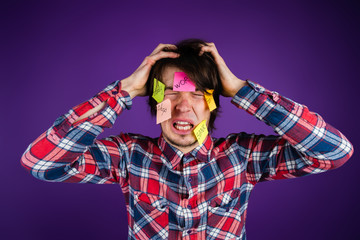 The man grabs his head and cries. A man is shocked by his obligations and routine. Stickers on face...