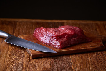 Strong professional man's hands cutting raw beefsteak, selective focus, close-up