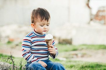 little cute boy eating ice cream three years very appetizing, amid nature, green grass