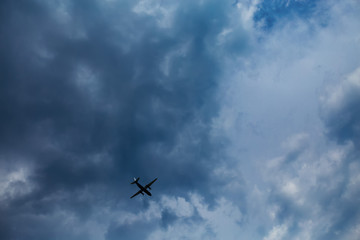 Fototapeta na wymiar dark blue sky with clouds and an airplane flying in bad weather