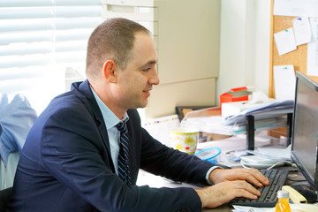 Close-up of office worker. Man Working At Desk In Busy Creative Office. Businessman working at the computer.
