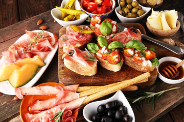 Italian antipasti wine snacks set. Cheese variety, Mediterranean olives, pickles, Prosciutto di Parma, tomatoes, artichokes and wine in glasses