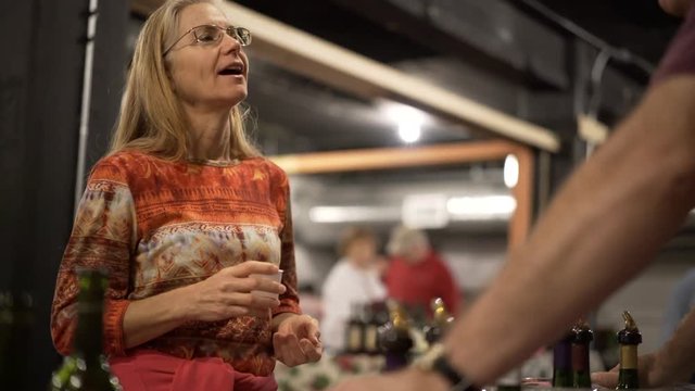 Beautiful, mature woman discusses wine at wine and food festival indoors