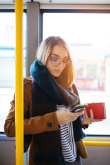 Young happy woman standing in city bus and using mobile phone.  © hedgehog94