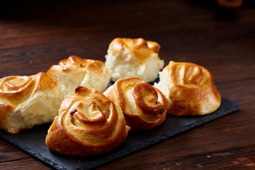 Homemade rose buns on wooden cutting board over rustic vintage background, close-up, shallow depth of field