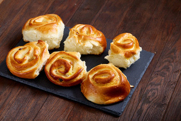 Homemade rose buns on wooden cutting board over rustic vintage background, close-up, shallow depth of field