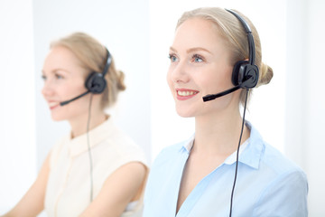 Image of bright call center. Focus on young beautiful woman in a headset