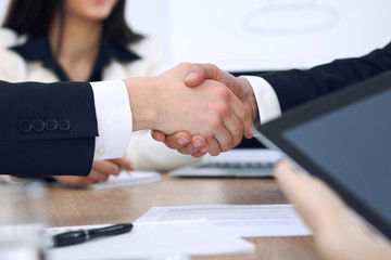 Close up of business people shaking hands at meeting or negotiation in the office. Partners are satisfied because signing contract