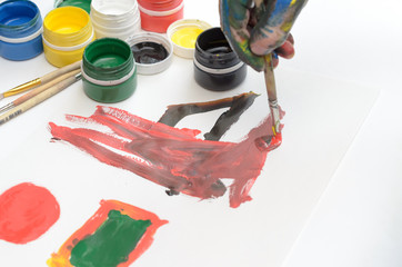 A child's hand in paint paints gouache on white paper.