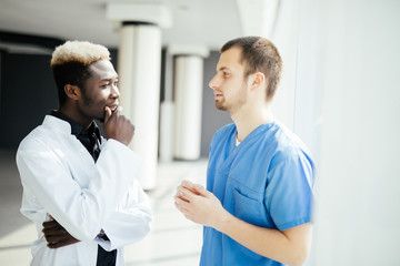 Obraz premium Mixed race two Doctors talking As They Walk Through Hospital