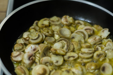 sliced mushrooms fried in butter in a pan, vegetarian dish