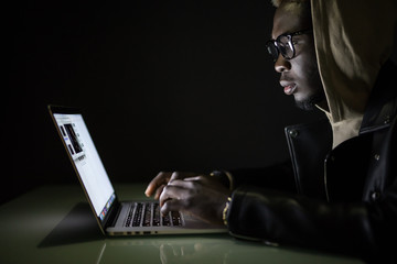 Hacker attack the server in the dark. Afro american hacker hack server from laptop in darkness