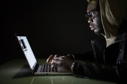 Hacker attack the server in the dark. Afro american hacker hack server from laptop in darkness