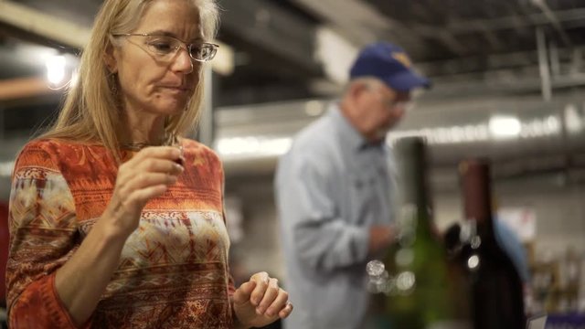 Beautiful, mature woman tastes wine sample at wine and food festival indoors
