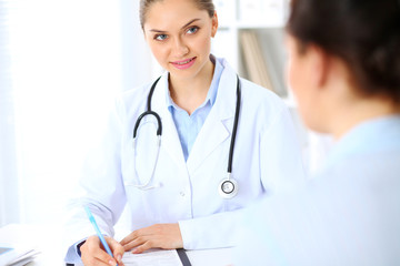 Fototapeta premium Friendly smiling doctor and patient sitting at the table