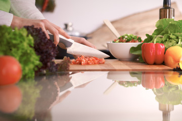 Close Up of human hands cooking vegetable salad in kitchen on the glass table with reflection. Healthy meal, and vegetarian food concept