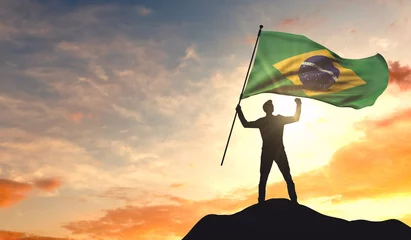 Fotobehang Brazil flag being waved by a man celebrating success at the top of a mountain. 3D Rendering © ink drop