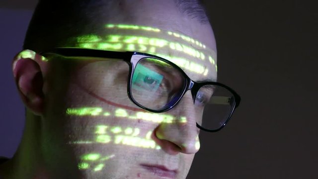 The programmer works at the computer over the program in a dark room. The hacker performs banned financial transactions with electronic money.