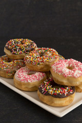 Various Flavors of Sprinkle Donuts on a Slate Counter