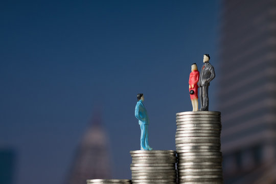 Figure Miniature Businessman Of Small People Investor And Office Worker Secretary Standing On Stack Of Coin, With Modern City Background For Money And Financial Business Concept.