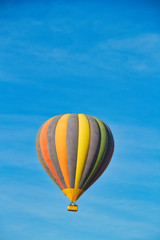 A hot air balloon rising under partly cloudy skies.