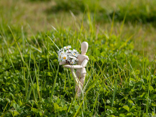 Wooden mannequin with a bouquet of flowers in his arms on springtime Romanticism and love concept
