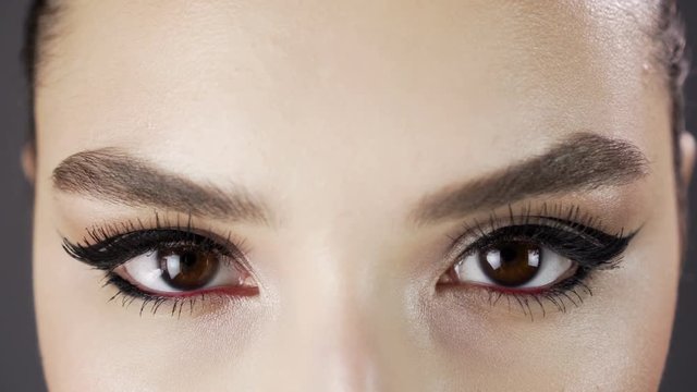 Eyes of a beautiful sexy girl. Fashion model posing on a dark background for studio photo shoot. Expressive and stylish makeup. Close up. Slow mo