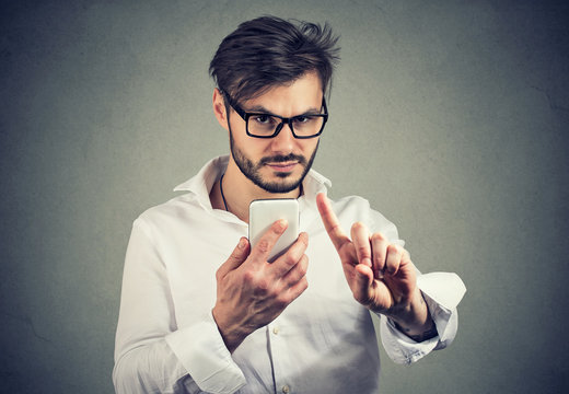 Man with smartphone showing rejecting sign