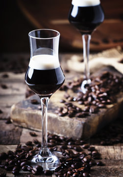 Two-layer cocktail with coffee liqueur, vintage wood background, selective focus