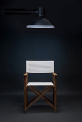 Folding director's chair in a photo studio on a blue background.