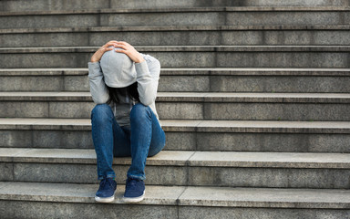 Upset woman sitting alone on city stairs