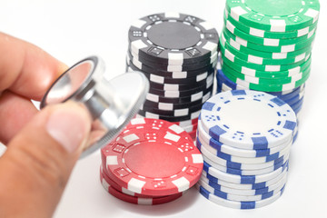 stethoscope and pile of casino chips on white background